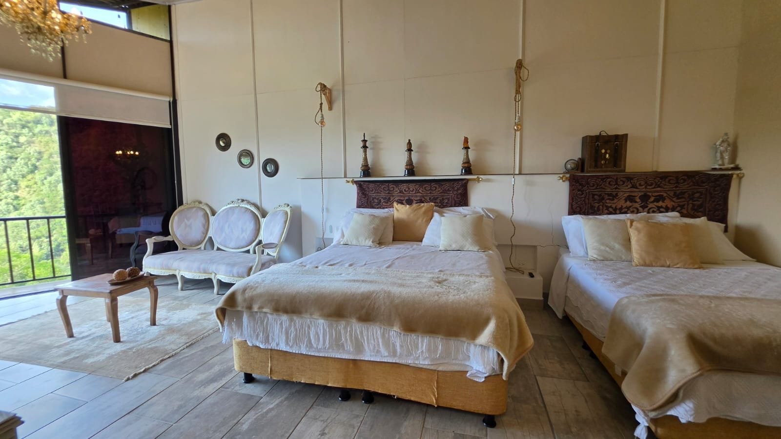 Ein geräumiges Schlafzimmer mit zwei Betten, einer Sitzecke mit Sesseln und einem Balkon mit Blick.
