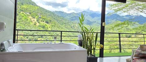 A bathroom with a large bathtub and a view of a mountainous landscape.