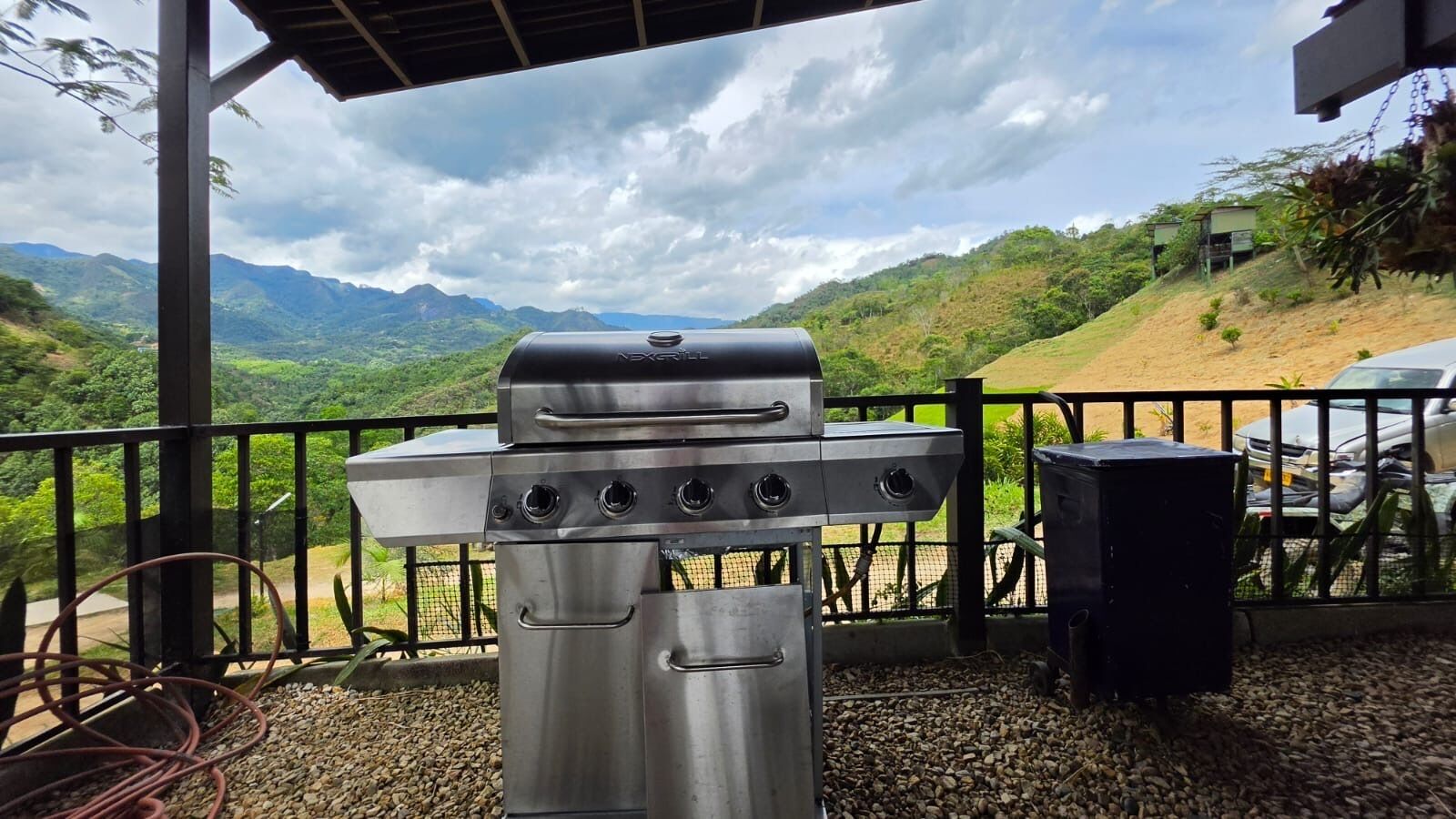 A barbecue grill on an outdoor patio with a view of mountains and a cloudy sky.