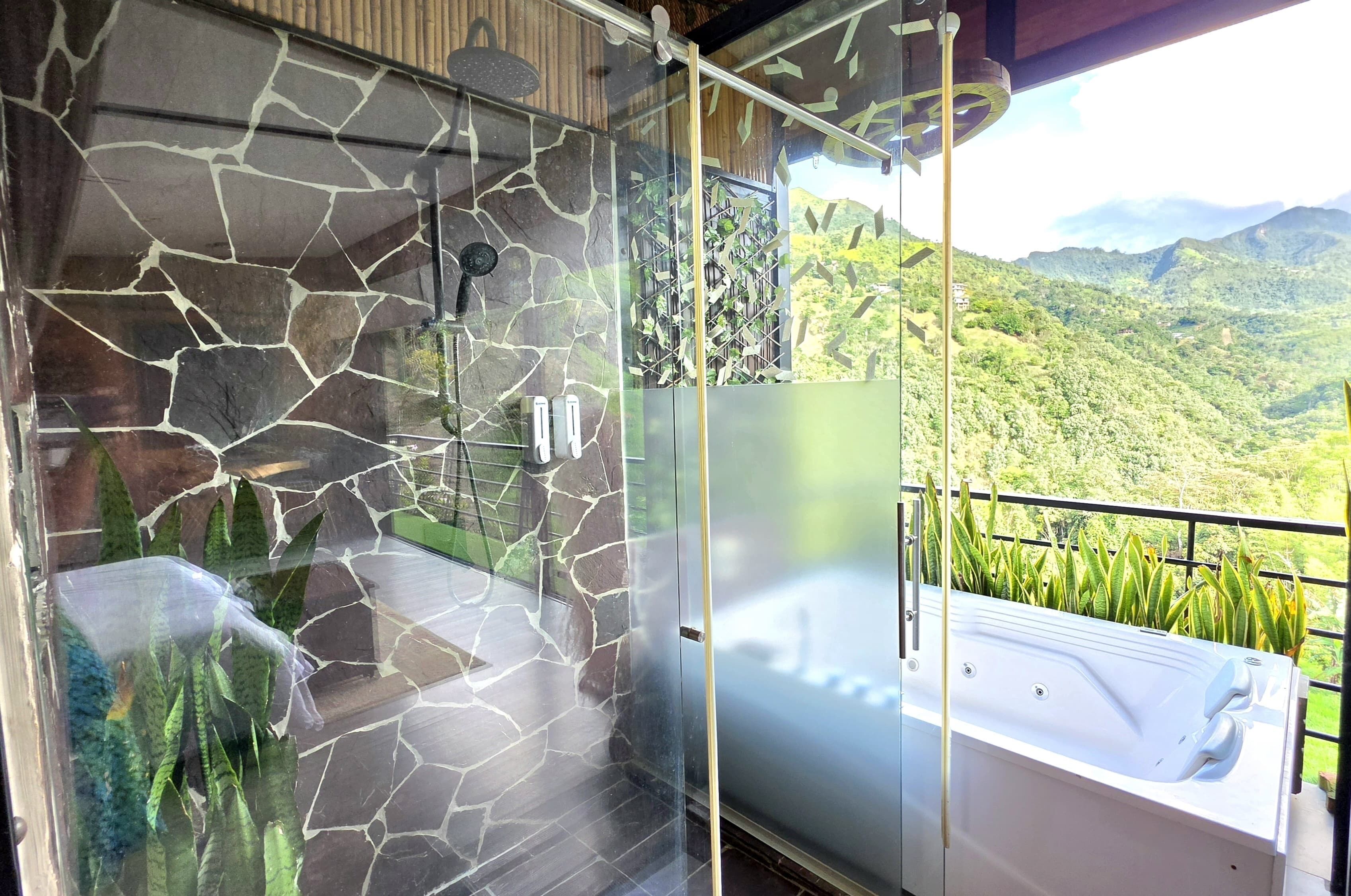 A glass-enclosed bathroom with a stone wall, a shower, and a bathtub.