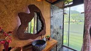 Un baño con un espejo grande, tocador de madera y vistas a un lago.