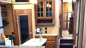 A compact living space with a kitchenette, a sofa, a small table, and a staircase leading to an upper level.