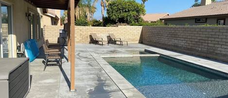 Una piscina con sillones de descanso y zona de barbacoa.