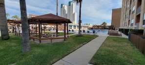 A hotel courtyard with a pool, lounge chairs, a gazebo, and palm trees. - * BBQ Pits *Private Beach Access * Pool & Hot Tub (South Padre Island)