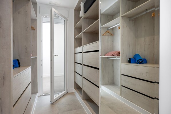 Un dressing accessible sans porte, avec des étagères en bois et une tringle pour suspendre les vêtements.