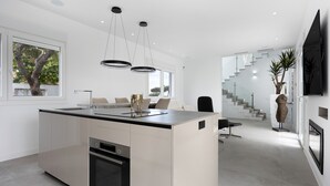 Een moderne keuken met een centraal eiland, inbouwoven en hanglampen.
