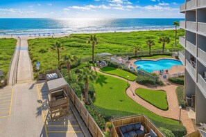 A resort with a swimming pool, a beach view, and a well-maintained lawn.