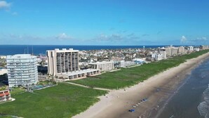 Un paisaje urbano costero con una extensa playa, edificios modernos y cielo despejado.