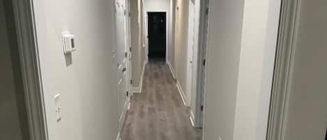 A long, narrow hallway with a wooden floor and white walls.