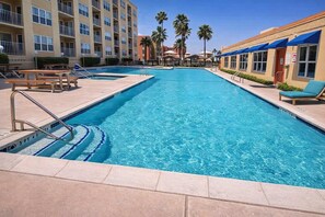 A swimming pool with a 3ft depth marker, lounge chairs, and a building with balconies. - Great Pool " Beach Access " Small Family Perfect (South Padre Island)