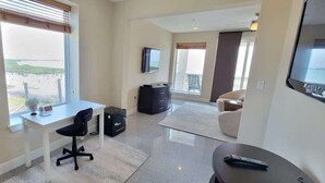 A hotel room with a desk, chair, TV, and a view of the outdoors. - 3-Level Bayfront | Boat Dock | Walk-In Pool | SPI (South Padre Island)