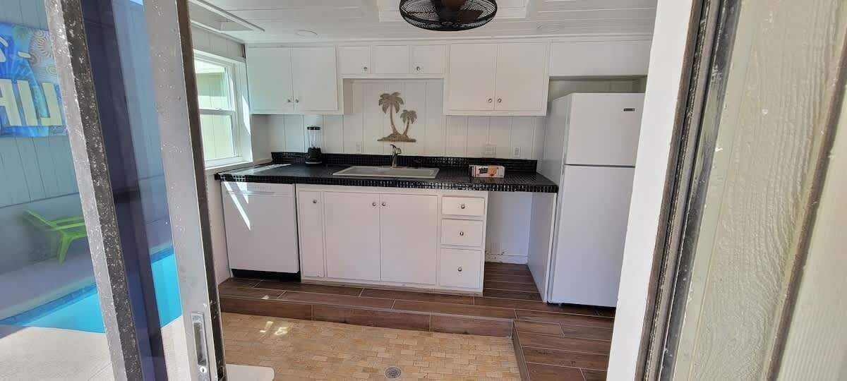 Uma cozinha compacta com armários brancos, bancada preta e uma pequena ilha.