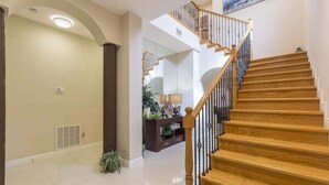 A modern interior with a wooden staircase, a hallway leading to a living area, and a large mirror reflecting the space. - Big Private Luxury Home in Beach Gated Community (South Padre Island)