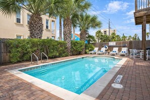 A rectangular pool with a tiled edge, surrounded by palm trees and a wooden fence. - * EZ to Beach Sleeps Many * Very Clean * Pool (South Padre Island)