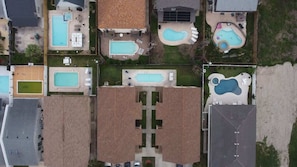 Vue aérienne d’un quartier résidentiel comprenant plusieurs piscines, une cour centrale et des maisons environnantes.