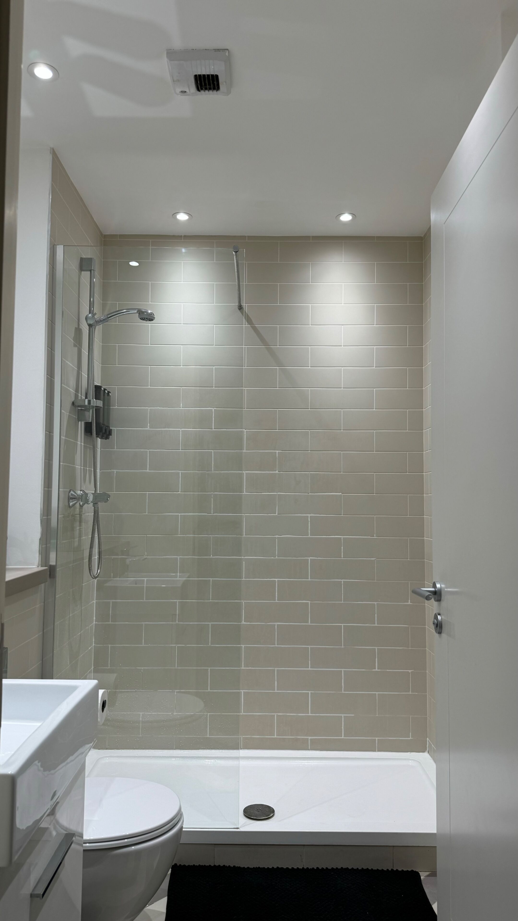 A modern bathroom with a glass-enclosed shower, a white toilet, and a bathtub.