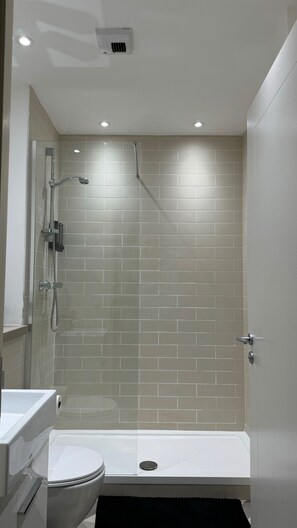 Ein modernes Badezimmer mit einer Duschkabine, einer weißen Toilette und einer Badewanne.