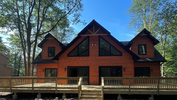 A wooden cabin with a central gable roof, two side gables, and a symmetrical front facade.