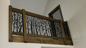 A wooden railing with a tree design, a mirror, and a white wall.