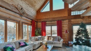 L’intérieur d’un chalet accueillant, doté de grandes fenêtres, de murs en bois et d’une cheminée.