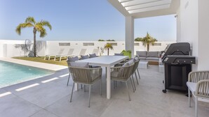 A covered outdoor area with a pool, a dining table with chairs, a barbecue grill, and lounge seating. - Villa 'Habana' with Lake View, Wi-Fi and Air Conditioning (Poblado de Sancti Petri)