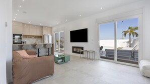 A modern living room with a sofa, a coffee table, a flat-screen TV, and a fireplace. - Villa 'Habana' with Lake View, Wi-Fi and Air Conditioning (Poblado de Sancti Petri)