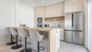 A modern kitchen with a central island, bar stools, a stainless steel refrigerator, and built-in appliances. - Villa 'Habana' with Lake View, Wi-Fi and Air Conditioning (Poblado de Sancti Petri)