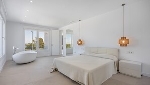 A modern bedroom with a large bed, a freestanding bathtub, and a view through the door. - Villa 'Habana' with Lake View, Wi-Fi and Air Conditioning (Poblado de Sancti Petri)