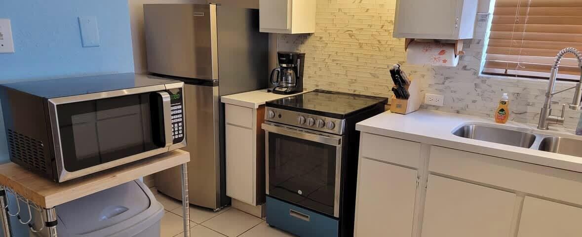 A compact kitchen with a microwave, stove, and sink.