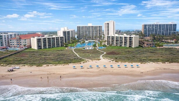 A beachfront hotel with multiple high-rise buildings, a sandy beach with umbrellas, and a view of the ocean. - * Gas BBQ * Heated Pool * Direct Beach  Very Large (South Padre Island)