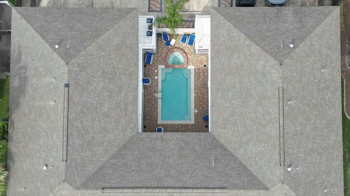 Et luftfoto viser et tag med et poolområde, hvor et centralt pool er omgivet af liggestole og en palme.