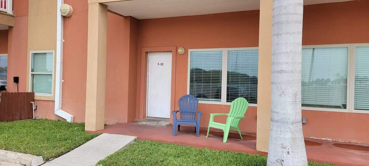 Un edificio con una puerta que tiene la etiqueta “F-182” y dos sillas afuera.