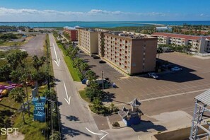 Un hôtel doté d’un parking, offrant une vue sur l’océan et dont on aperçoit un pont au loin.