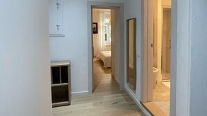A hallway with wooden flooring leading to a bedroom and bathroom.
