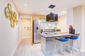 Una cucina moderna con isola centrale, elettrodomestici in acciaio inossidabile e un elemento decorativo a parete.
