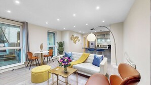 Un salon moderne comprenant un canapé, des fauteuils, une table basse et un coin repas avec une table et des chaises.
