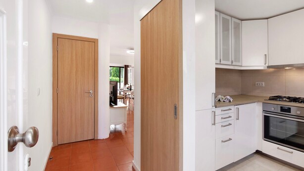 A modern kitchen with white cabinets, a wooden door, and a tiled floor. - Holiday Home 'Cool Motion 2149' with Private Terrace, Wi-Fi and Air Conditioning (Albufeira)