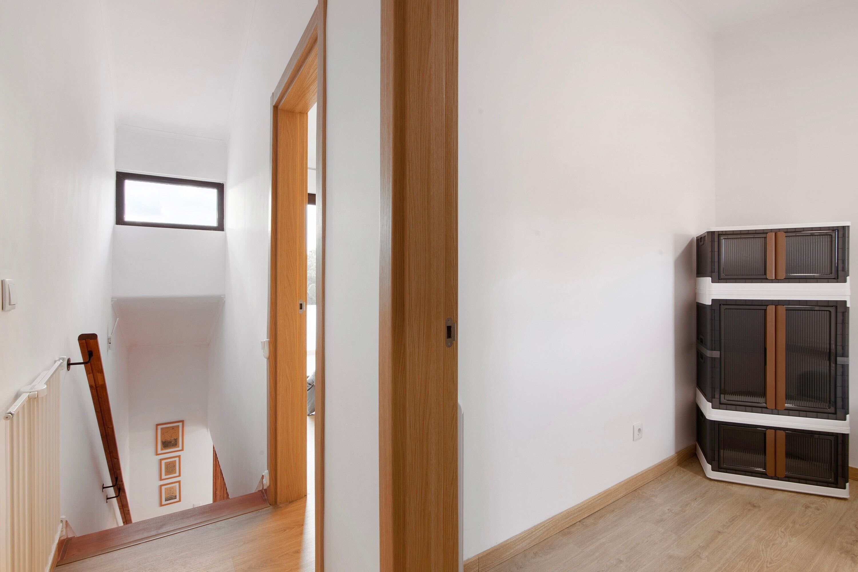 A hallway with a wooden door, a radiator, and a staircase leading to another room.