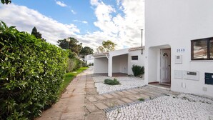 A white building with a number 2149, a paved pathway, and a hedge. - Holiday Home 'Cool Motion 2149' with Private Terrace, Wi-Fi and Air Conditioning (Albufeira)