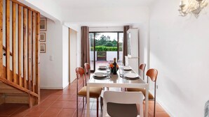 A dining area with a table set for four, a staircase, and a view of greenery outside. - Holiday Home 'Cool Motion 2149' with Private Terrace, Wi-Fi and Air Conditioning (Albufeira)