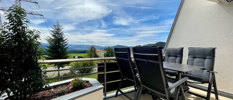 Un balcon avec une table et des chaises, une petite plante et une vue sur la campagne.