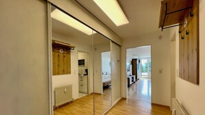 A modern hotel room with a large mirror, wooden flooring, a bed, a desk, and a radiator. - Modern "Waldluft" apartment with pool and sauna in Scheidegg in the Allgäu (Scheidegg)
