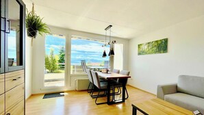 A modern living room with a dining area, wooden flooring, and a view of the outdoors. - Modern "Waldluft" apartment with pool and sauna in Scheidegg in the Allgäu (Scheidegg)