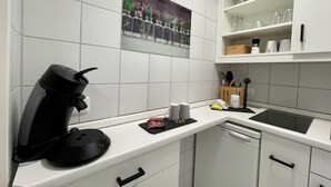 A modern kitchen with white cabinetry, a Bosch dishwasher, a coffee maker, and a decorative tile backsplash. - Modern "Waldluft" apartment with pool and sauna in Scheidegg in the Allgäu (Scheidegg)