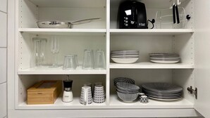 A kitchen with white shelves, a kettle, a coffee maker, and various glassware and plates. - Modern "Waldluft" apartment with pool and sauna in Scheidegg in the Allgäu (Scheidegg)