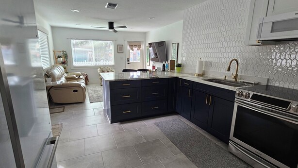 A modern kitchen with dark cabinetry, a built-in oven, and a microwave. - Downtown Getaway Casita (Bradenton)