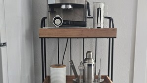 A kitchen area with a coffee machine, a kettle, and a tray with utensils. - Downtown Getaway Casita (Bradenton)