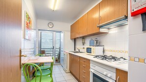 A kitchen with wooden cabinets, a gas stove, a microwave, and a sink. - Apartment 'Cool Motion Rocha Beach T1' with Balcony, Wi-Fi and Air Conditioning (Portimão)