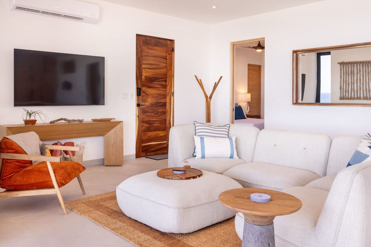 Una sala de estar moderna con un televisor de pantalla plana grande, una puerta de madera, un sofá y una mesa de centro.