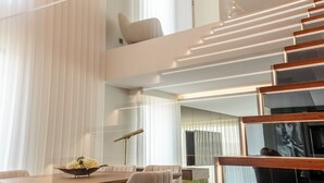 Un intérieur moderne comprenant un coin repas, un escalier et une rambarde en verre.